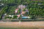 Vista aerea di un complesso alberghiero tra gli alberi, con piscina e accesso alla spiaggia.