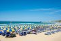 Spiaggia affollata con ombrelloni colorati e mare.